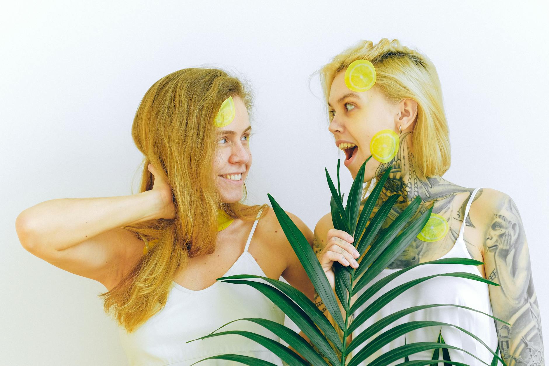 Deux femmes souriantes s'amusant avec des tranches de citron, exprimant la joie et le plaisir intérieur