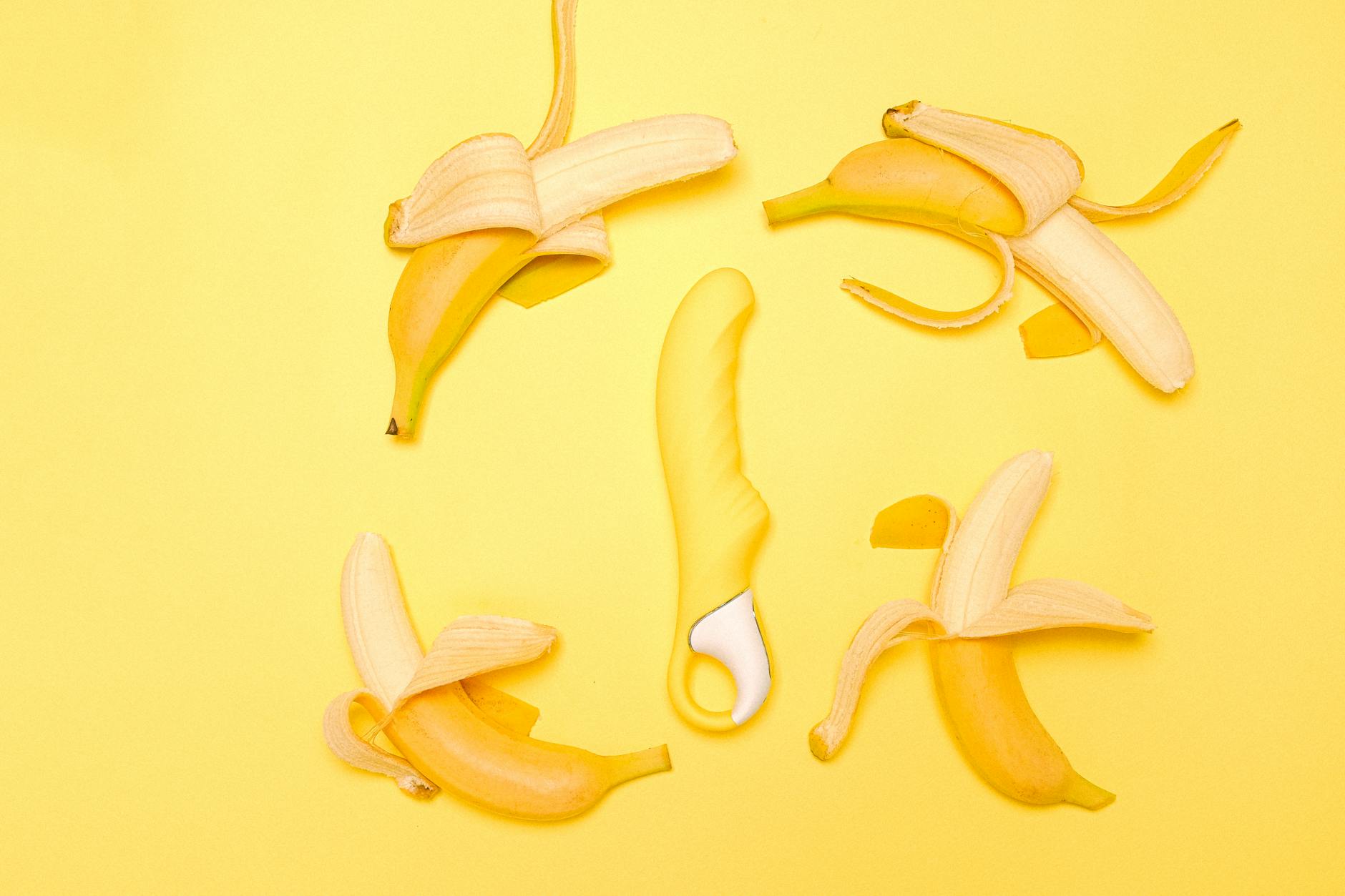 Vibromasseur Citron jaune vif entouré de bananes pelées sur fond jaune