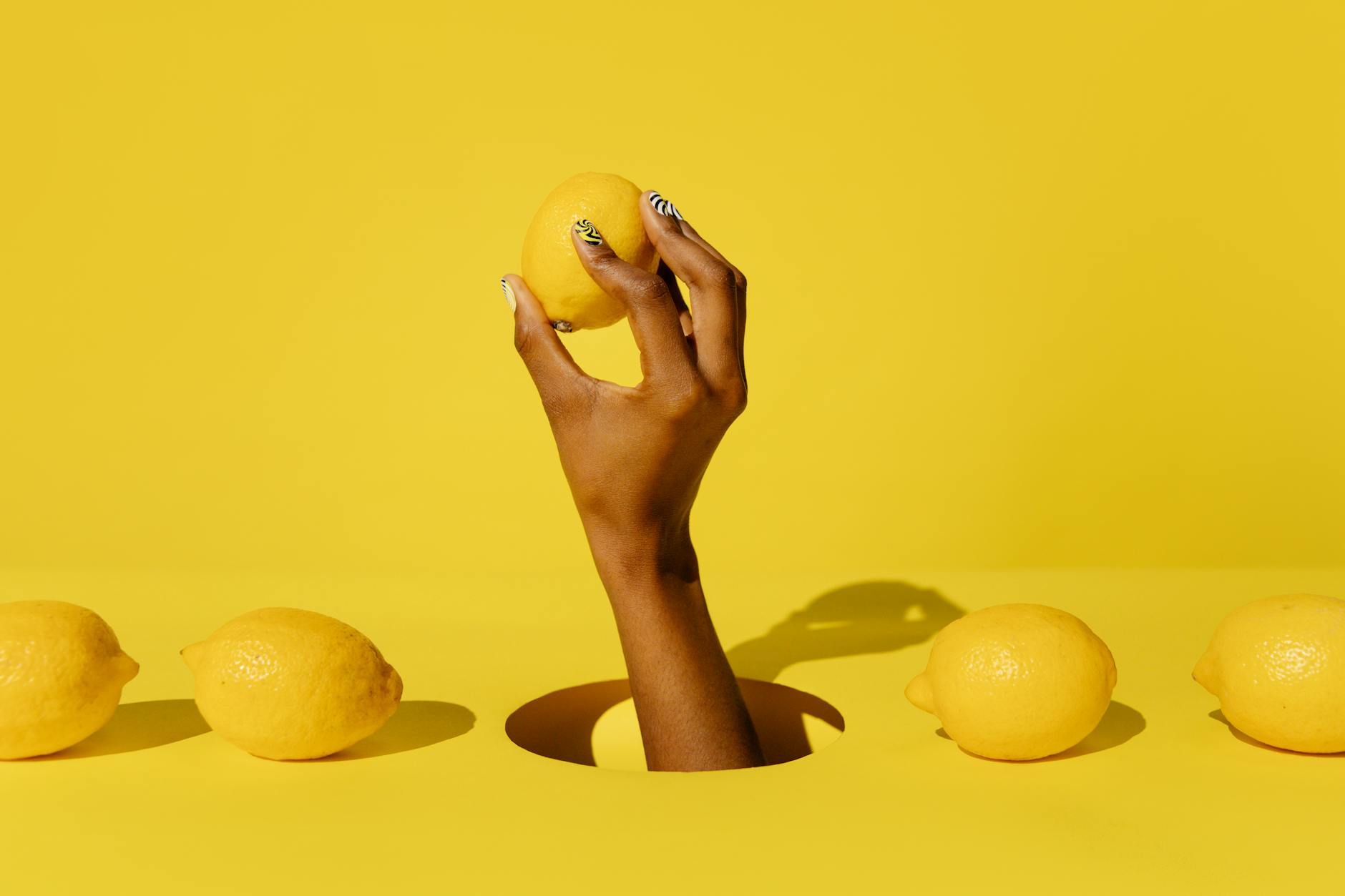 Main tenant un vibromasseur citron contre un fond jaune éclatant, exprimant une fraîcheur et une vitalité sensuelles.